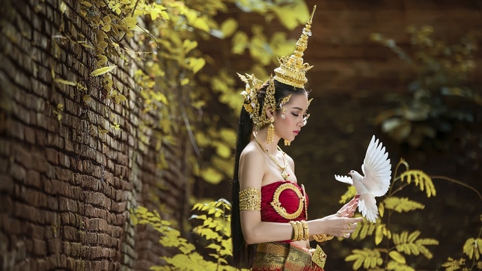 Woman in traditional attire holding a white dove