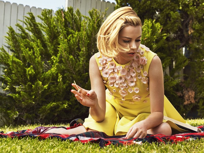 Elizabeth Banks sitting on a blanket in a backyard