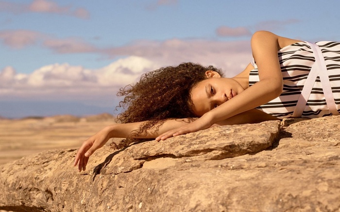 Young woman lying on rocks in a desert landscape