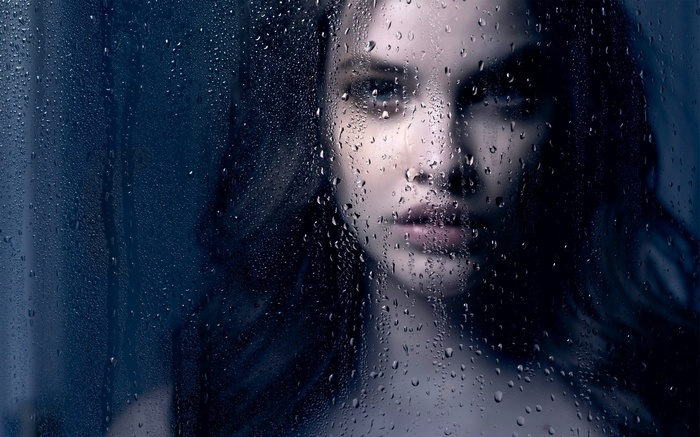 Woman behind a rain-covered window