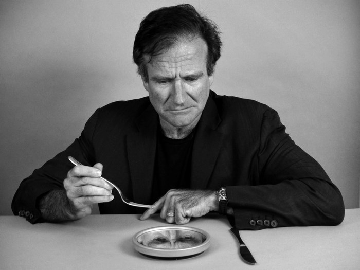 Robin Williams sitting at a table with a fork and a mirror