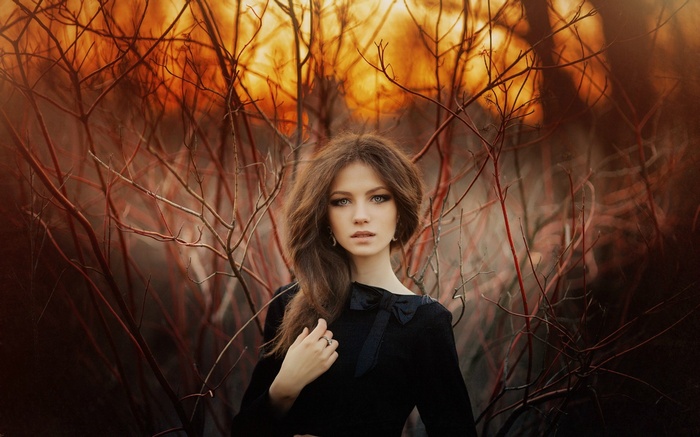 Woman in black dress among bare branches