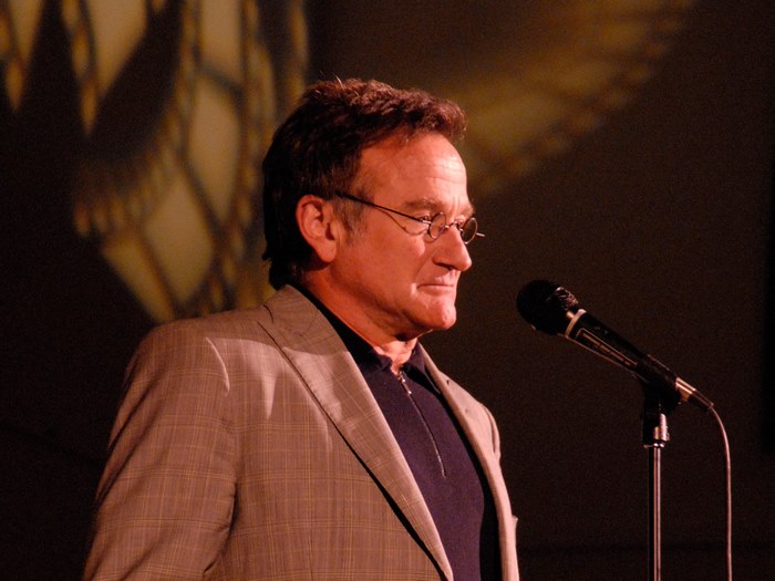 Robin Williams speaking at a microphone
