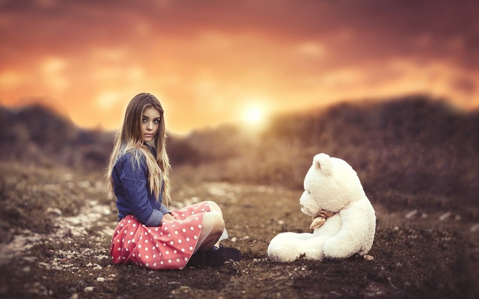 Girl with teddy bear at sunset