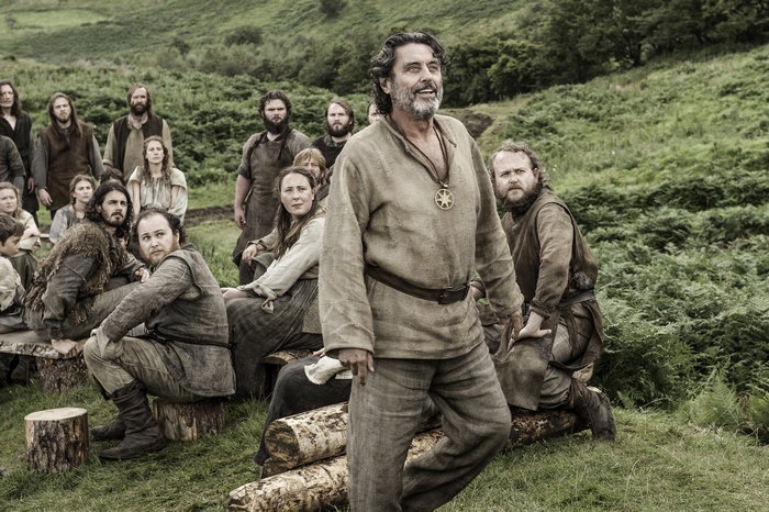 Ian McShane and villagers in a field