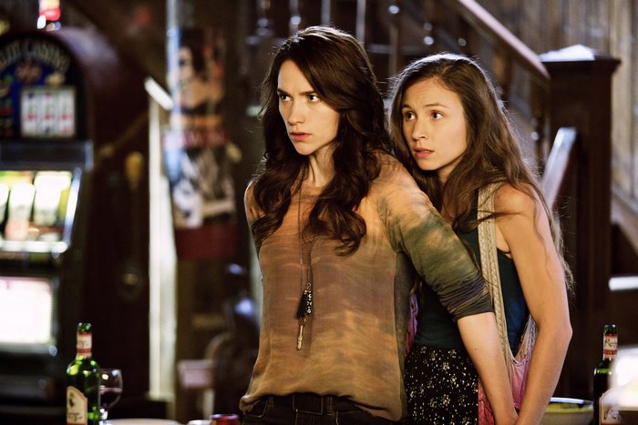 Melanie Scrofano and another woman in a dimly lit room