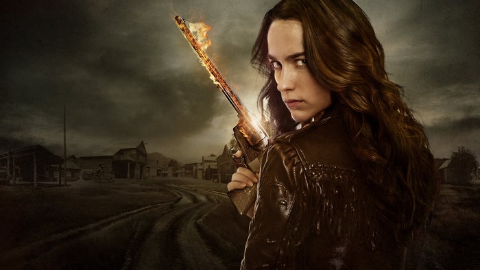 Melanie Scrofano with flaming rifle in Western town