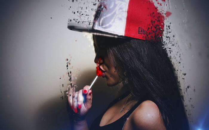 Woman in a baseball cap eating a lollipop