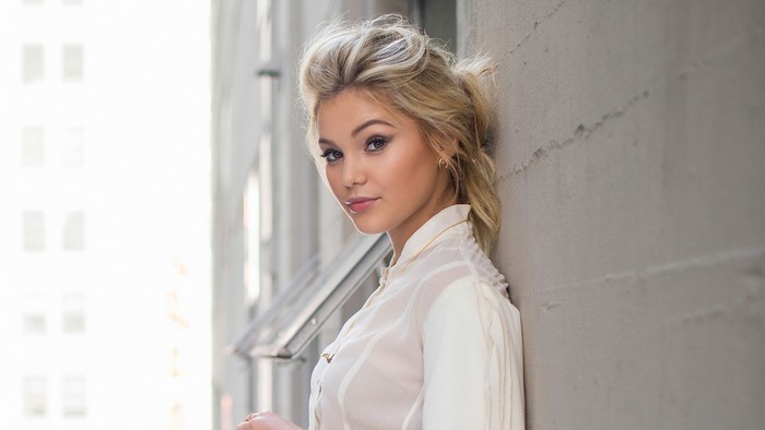 Olivia Holt leaning against a wall