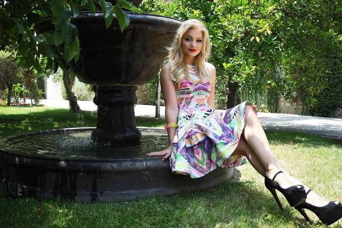 Olivia Holt sitting by a fountain