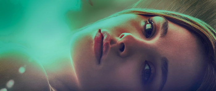 Close-up of a woman's face with green and purple lighting