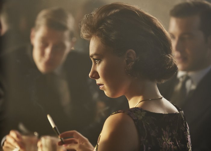 Vanessa Kirby in a dark dress holding a cigarette holder