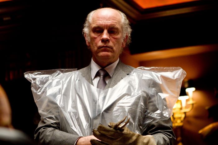 John Malkovich in a suit with plastic sheeting