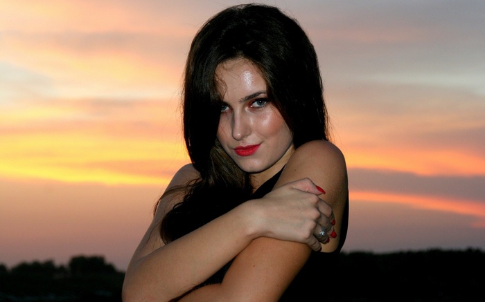 Woman with dark hair and red lipstick at sunset