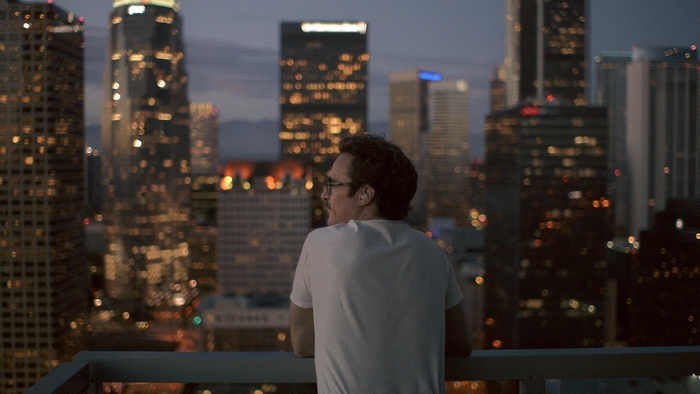 Joaquin Phoenix looking at city skyline at night