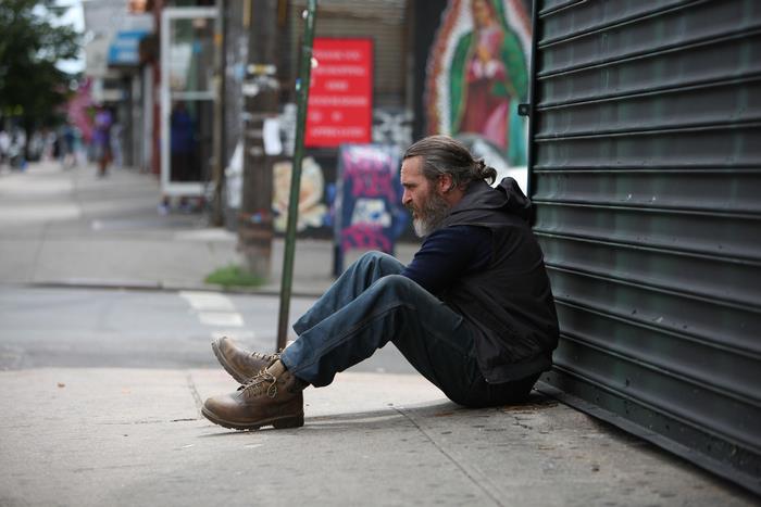 Joaquin Phoenix sitting on sidewalk