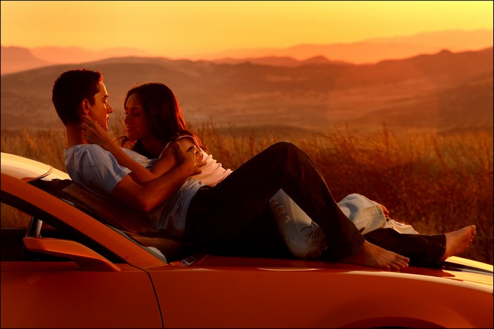 Shia LaBeouf and woman on car at sunset