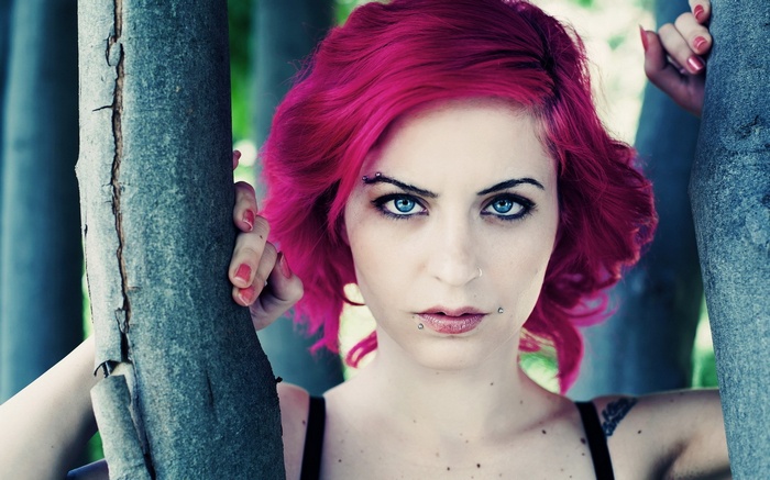 Woman with pink hair and piercings between trees