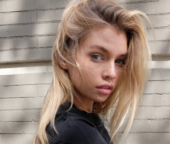Stella Maxwell posing against a brick wall