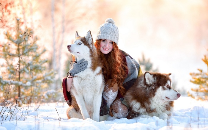 Woman with two huskies in a snowy forest