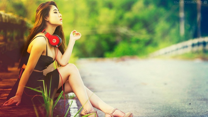 Woman with red headphones sitting by a road