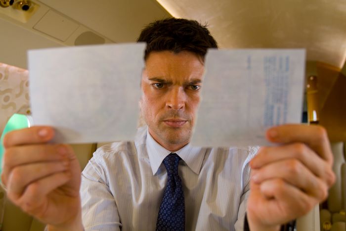Karl Urban on an airplane holding torn paper