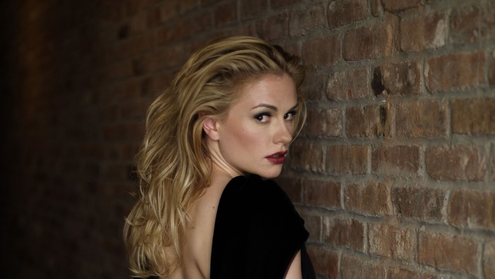 Anna Paquin leaning against a brick wall