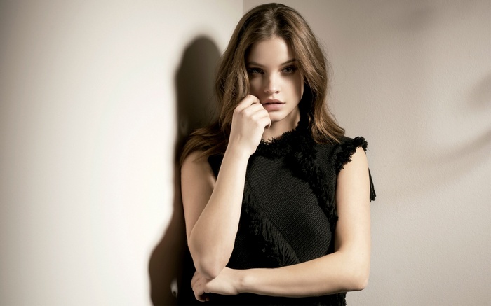 Woman in black dress leaning against wall