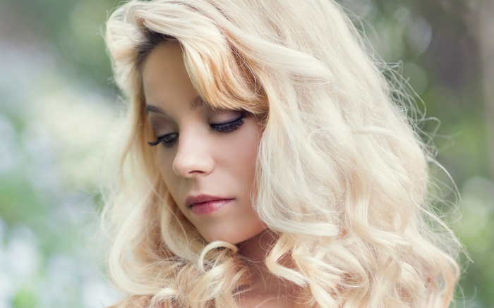 Woman with blonde curly hair looking down
