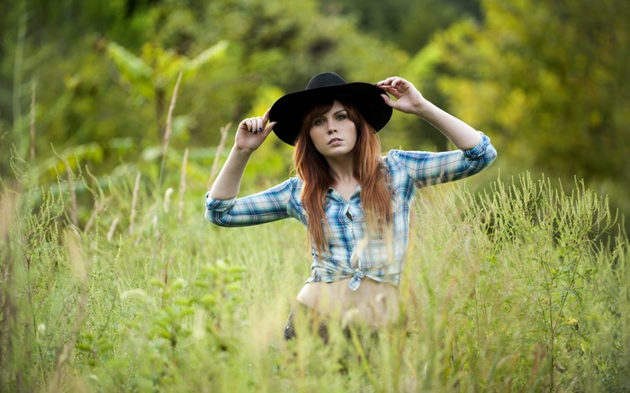 Woman in a hat and plaid shirt in a field
