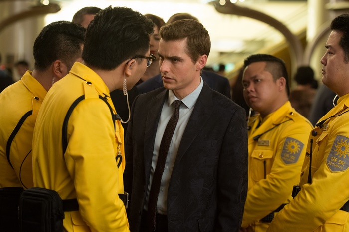 Dave Franco in a suit surrounded by security guards