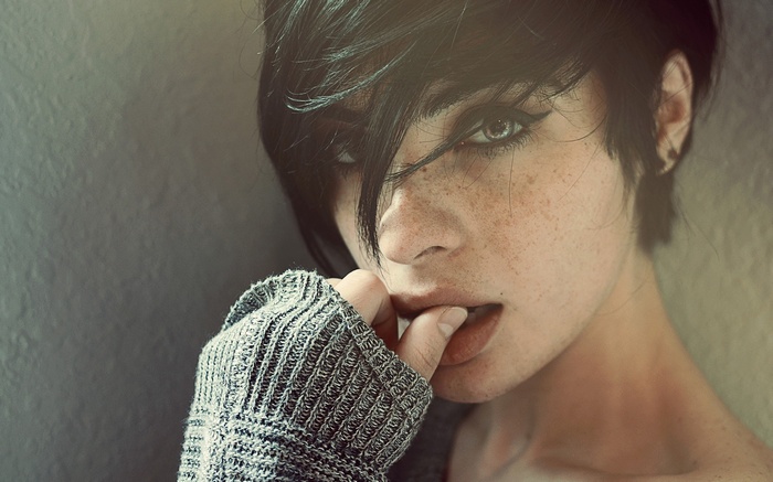 Woman with freckles biting her finger