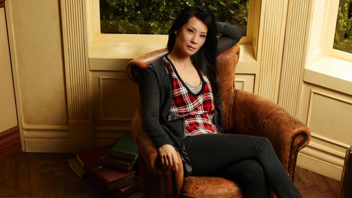 Lucy Liu sitting in a leather armchair