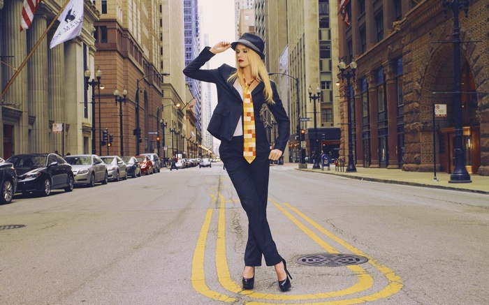 Woman in suit and hat posing in city street