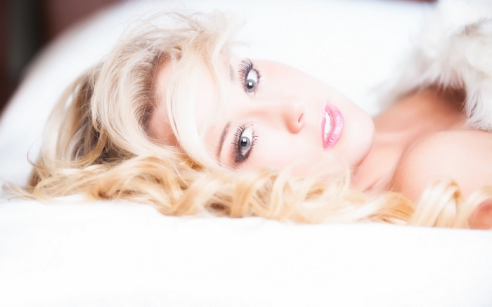 Blonde woman lying on a white surface