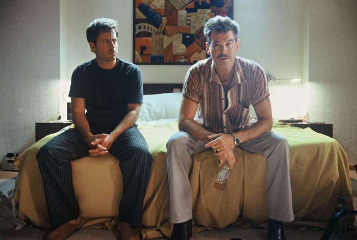Pierce Brosnan and another man in a hotel room