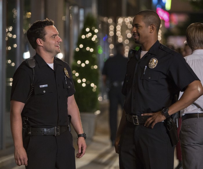 Two police officers talking on a street at night