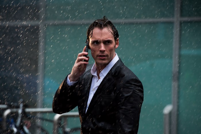 Sam Claflin in the rain on a phone call