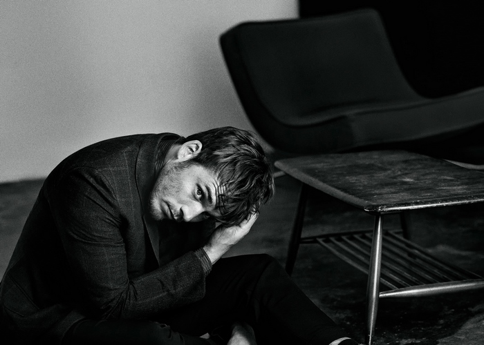 Sam Claflin sitting on floor