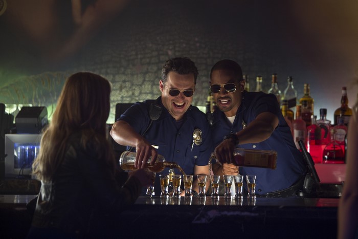 Two police officers pouring shots at a bar