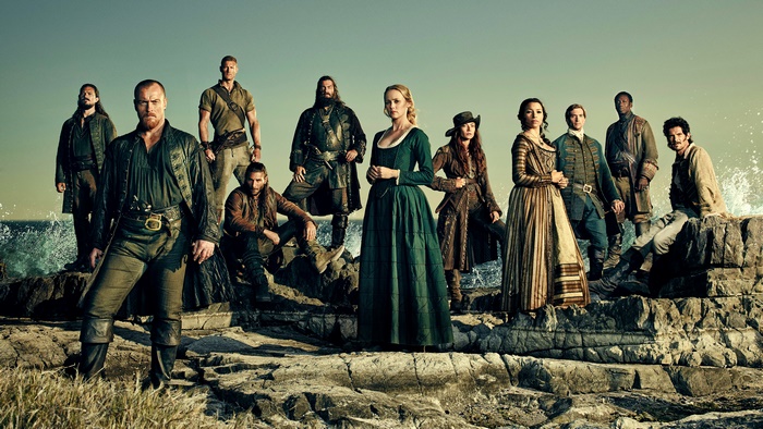 Cast of Black Sails on rocks by the sea
