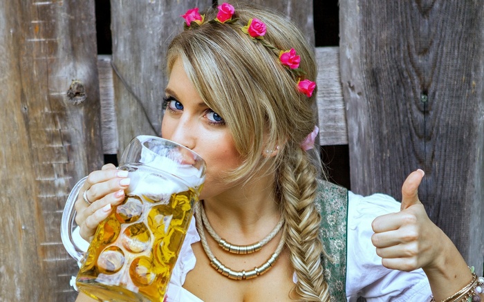 Woman in Dirndl drinking beer and giving thumbs up
