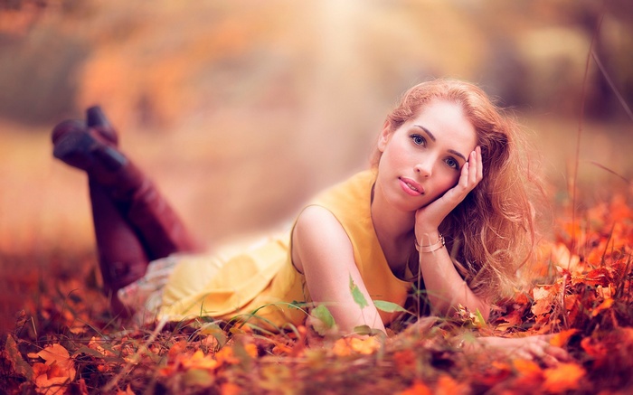 Woman lying in autumn leaves