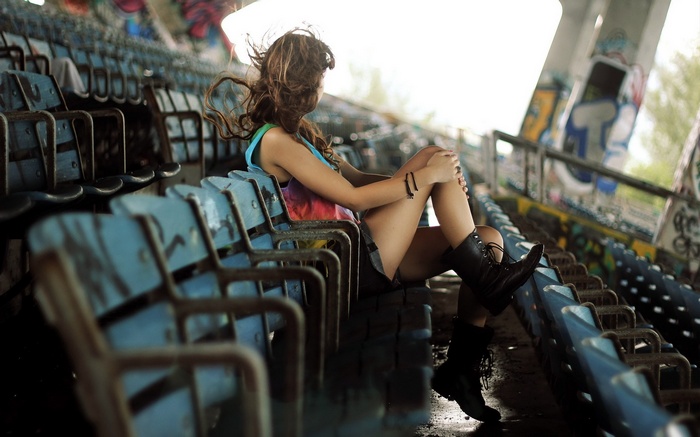 Woman sitting on stadium seats with graffiti