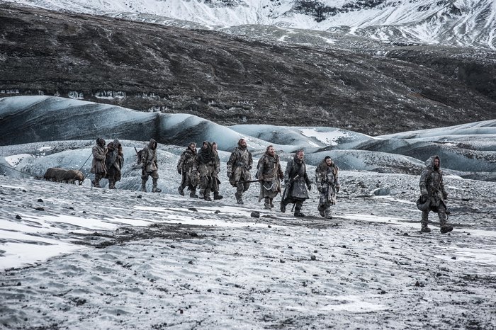Group of people and a dog walking on a glacier