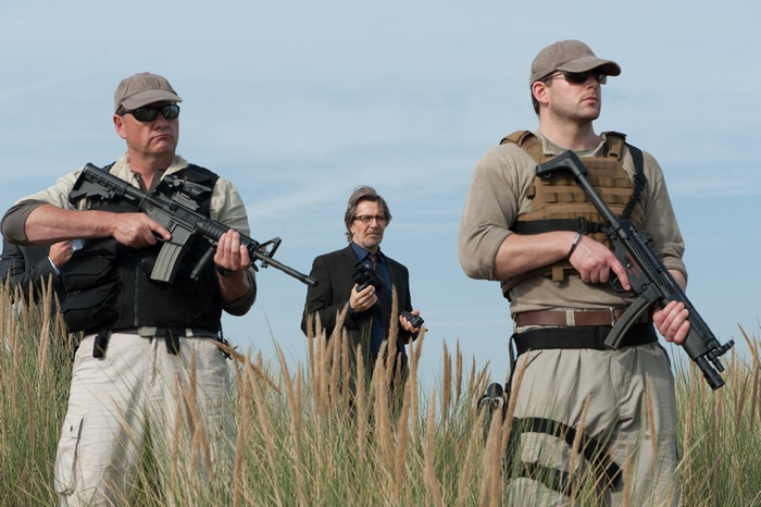 Gary Oldman with armed guards in field