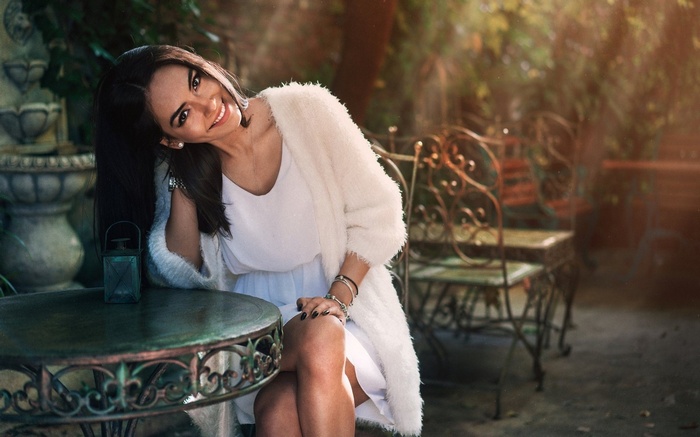 Woman in white dress and cardigan sitting at a table