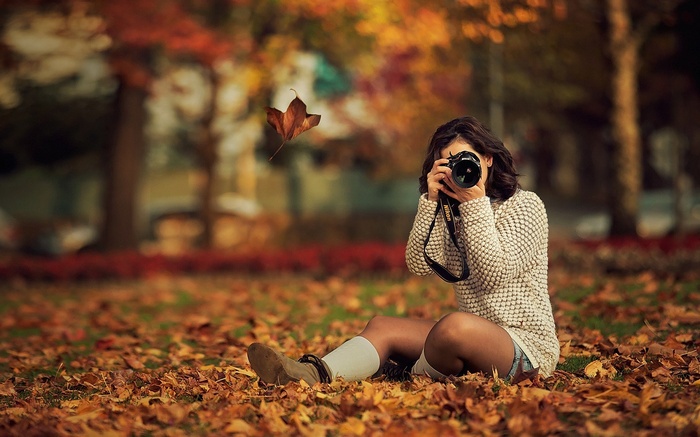 Woman taking a photo in autumn park