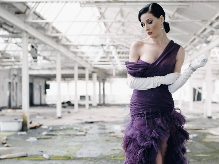 Dita Von Teese in a purple dress in an abandoned building