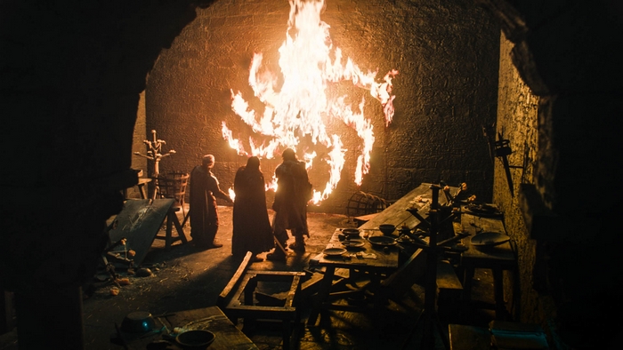 Three people in front of a burning symbol